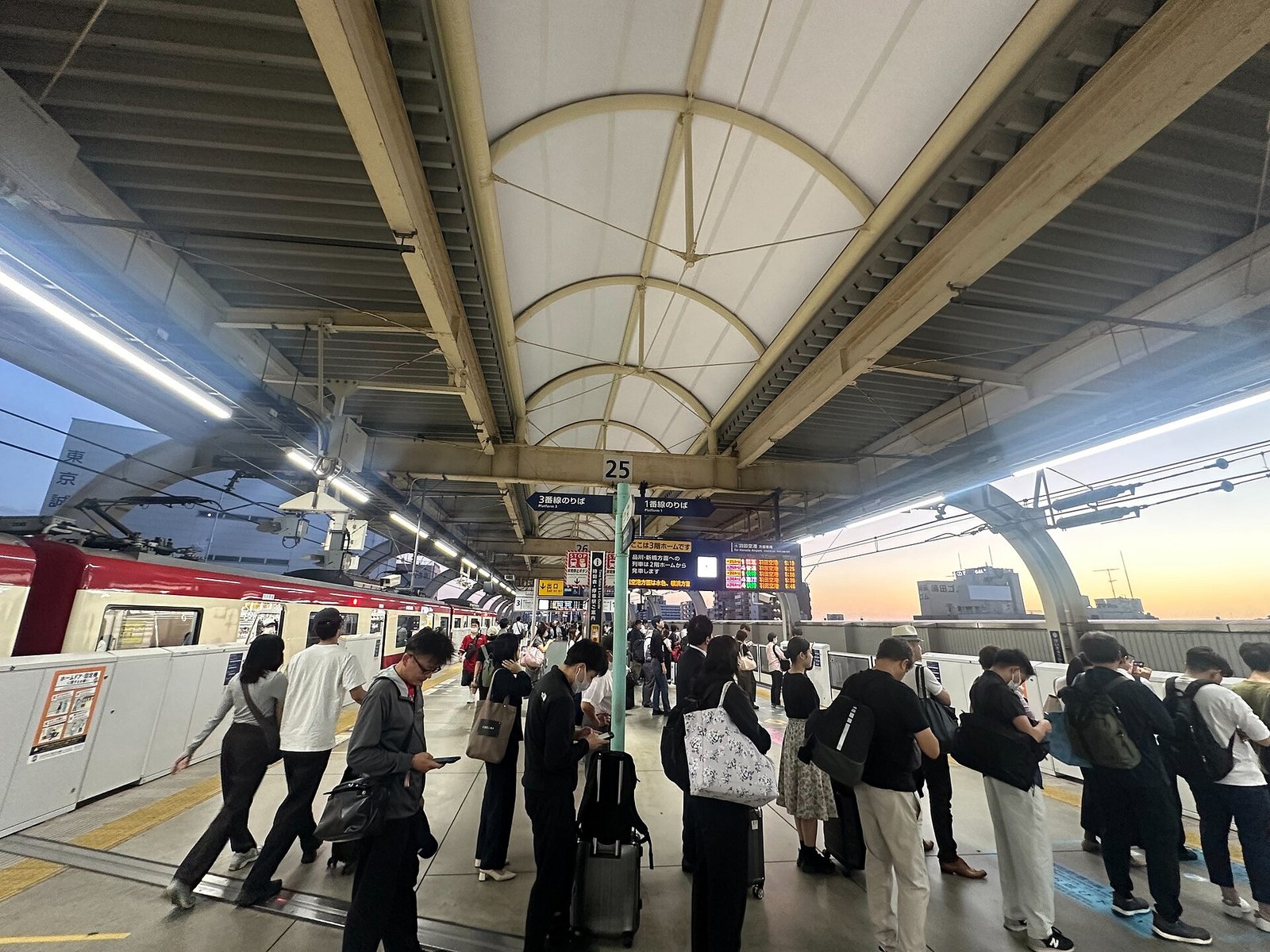 朝の駅のホームで電車を待つ人たち